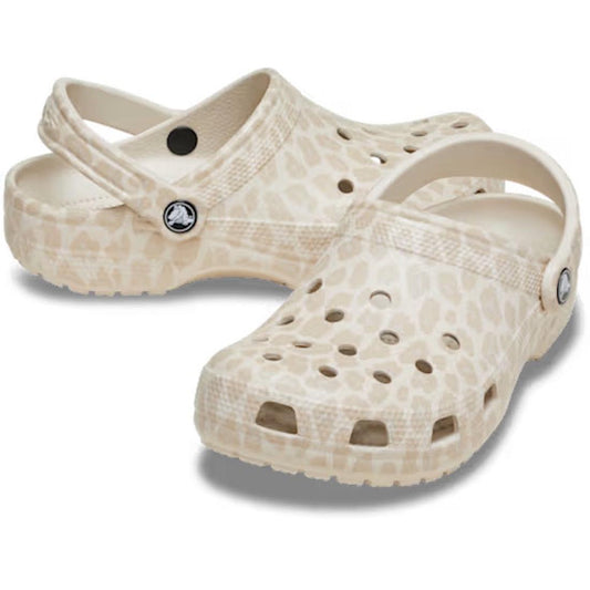 The Crocs Adults Classic Animal Clog in Almond Tint Leopard features a beige color with a subtle animal print, ventilation holes, and adjustable heel straps, displayed on a white background.