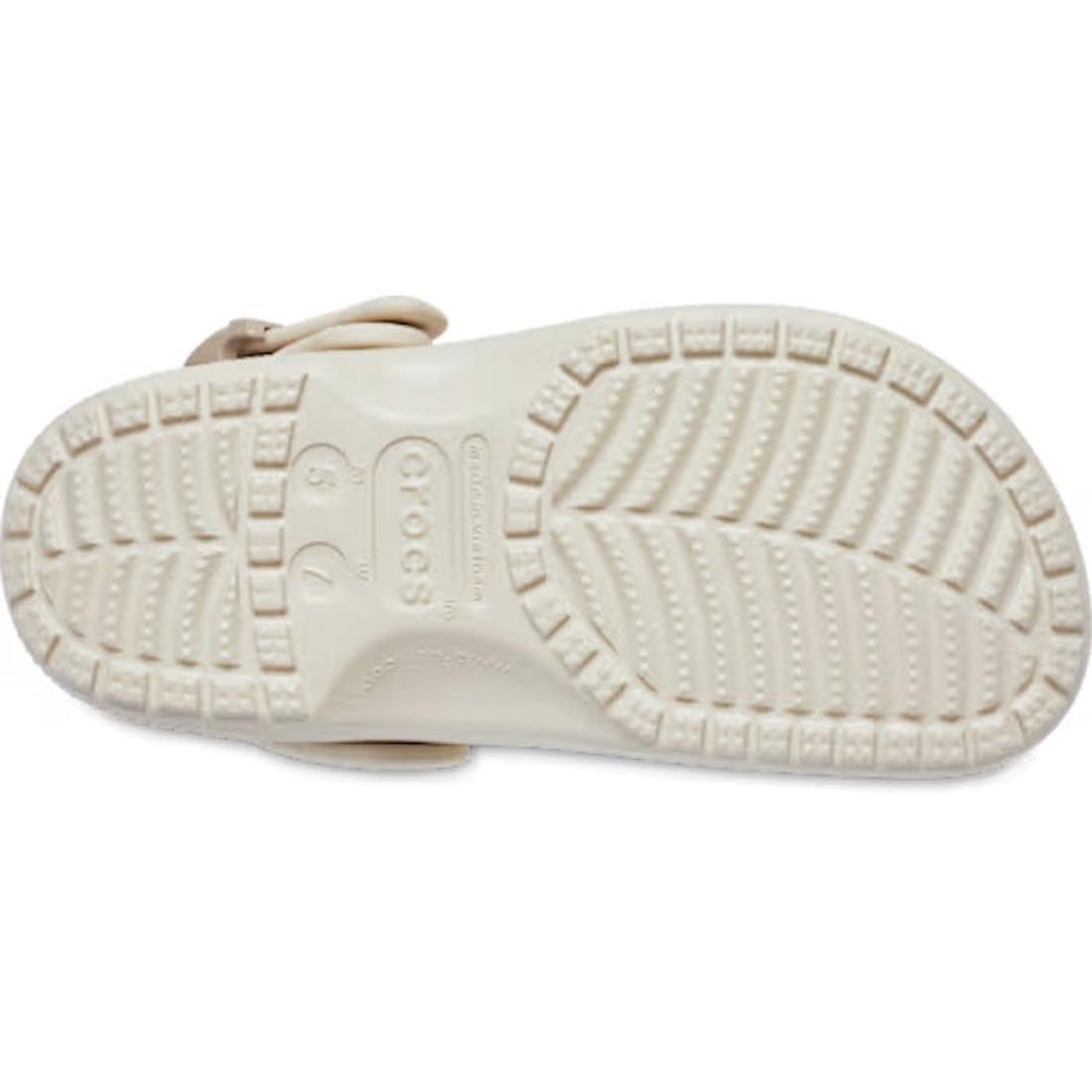 The image displays the sole of the Crocs Adults Classic Enamel Buckle Clog Frappe, a light-toned sandal with deep grooves, circular grip textures, and visible size and brand details. Crafted from Croslite foam for classic Crocs comfort., 198445415944, 198