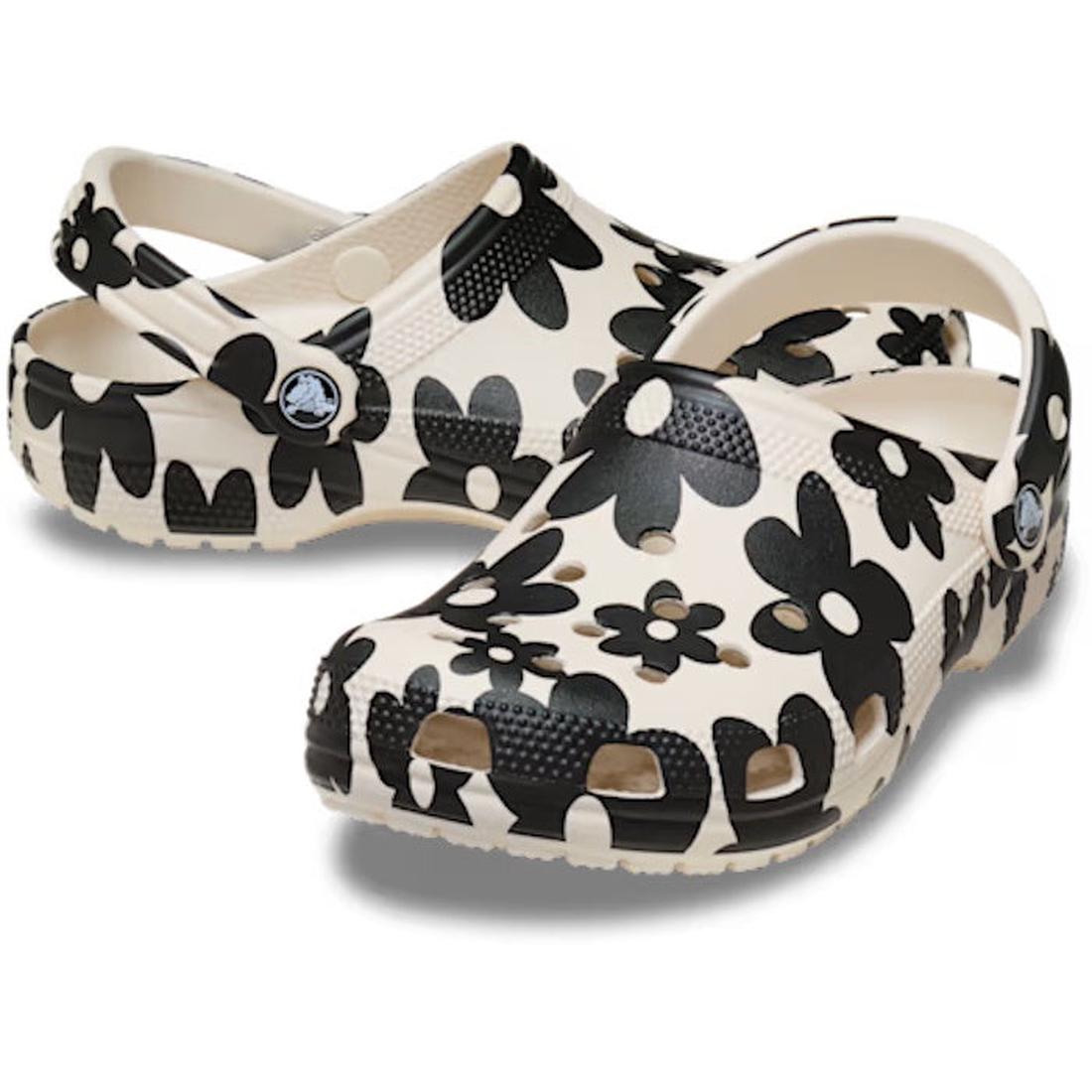 A pair of Crocs Adults Classic Pop Petals Summit White Multi clogs, showcasing black and white floral patterns with ventilation holes ideal for customizable Jibbitz charms and a secure heel strap, all set against a white background. Experience all-day Cro