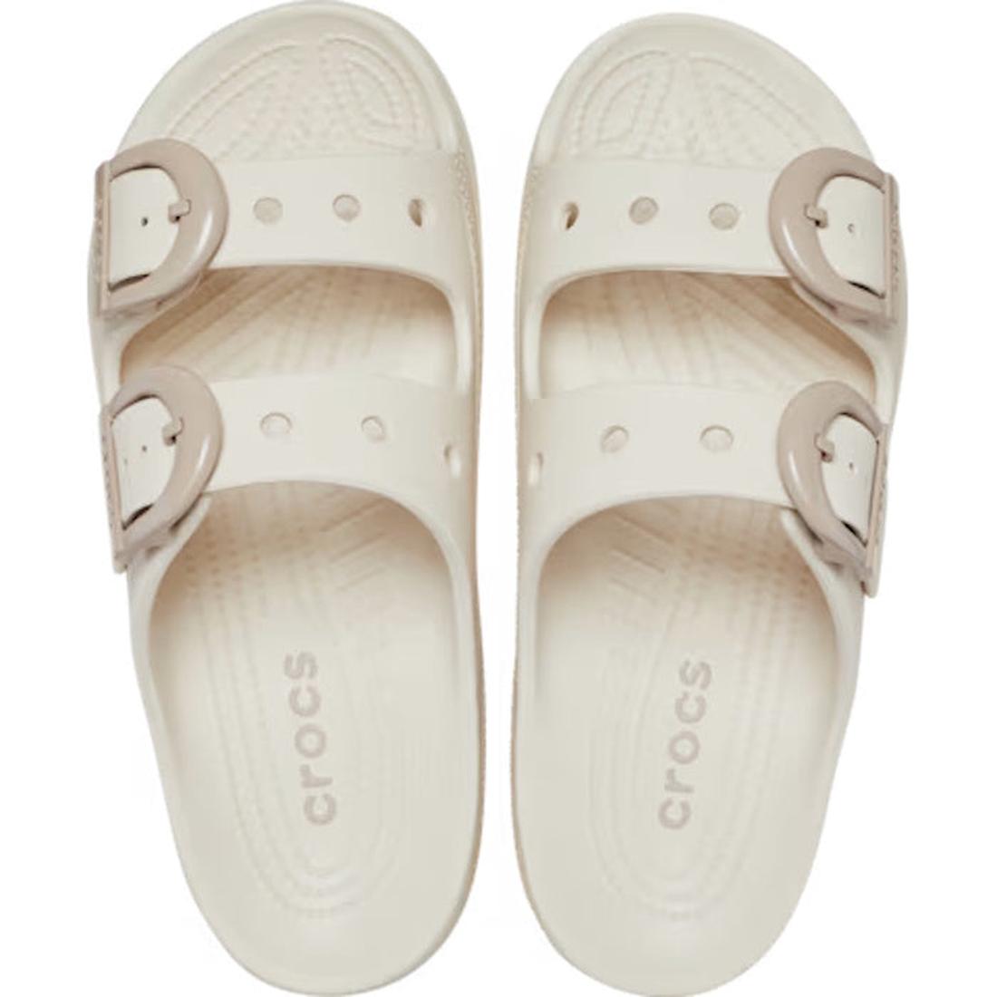 A pair of Crocs Womens Saturday Enamel Buckle Frappe Sandal Slides in a cream-colored frappe hue, featuring two beige adjustable enamel buckles on each sandal and shown from above on a white background—perfect for experiencing the signature comfort of Cro