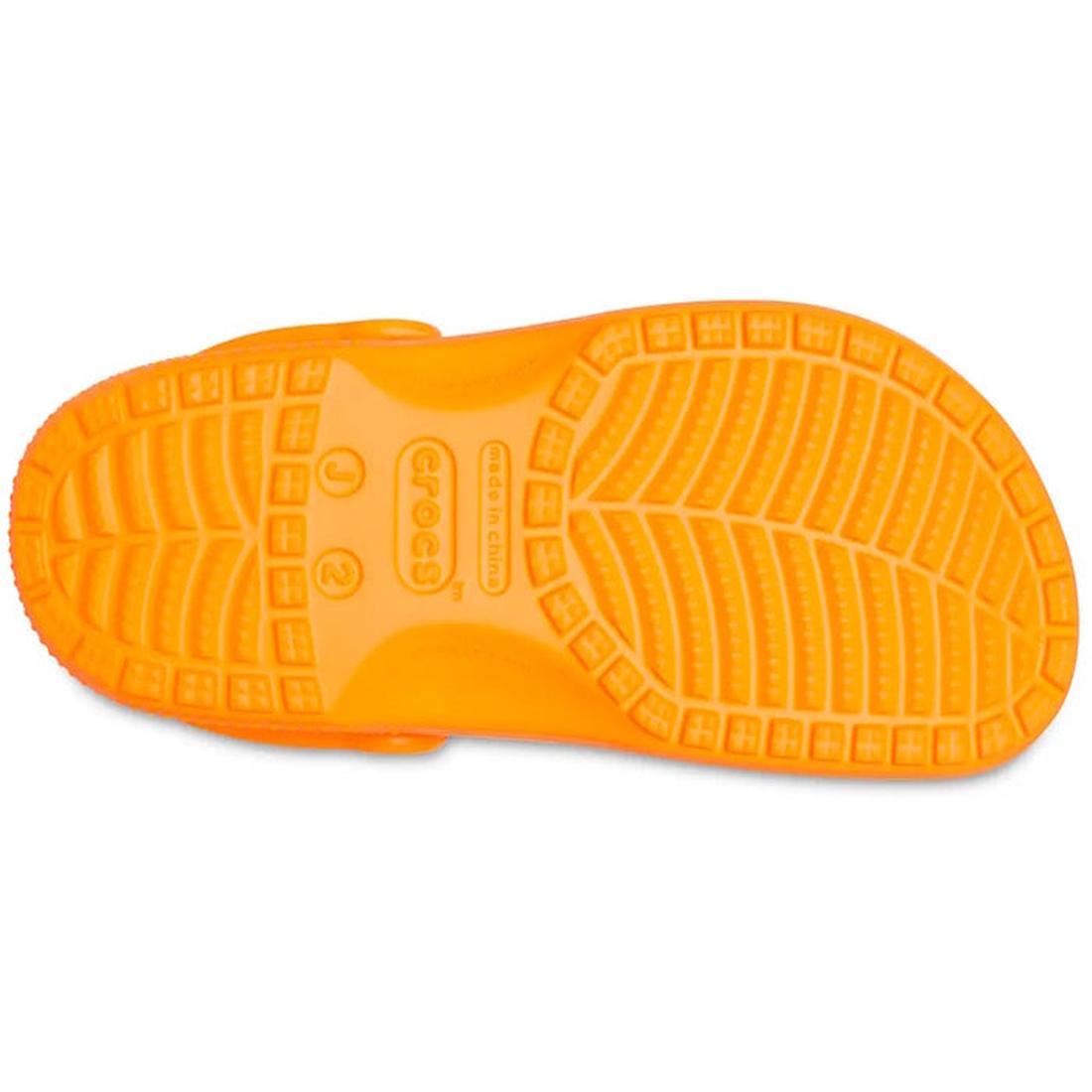 The Crocs Kids - Classic Clog Orange Zing (Junior Youths Sizes) is shown from the bottom, featuring a textured, water-friendly sole with traction grooves and the Crocs logo at the center., 191448894051, 191448894068, 191448894075, 191448894082, 1914488940