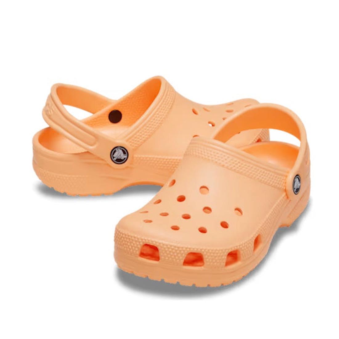 The Crocs Kids Toddlers - Classic Clog Electric Sunstone in toddler sizes feature ventilation holes, adjustable heel straps, and a water-friendly design. Shown here in light orange on a white background.
