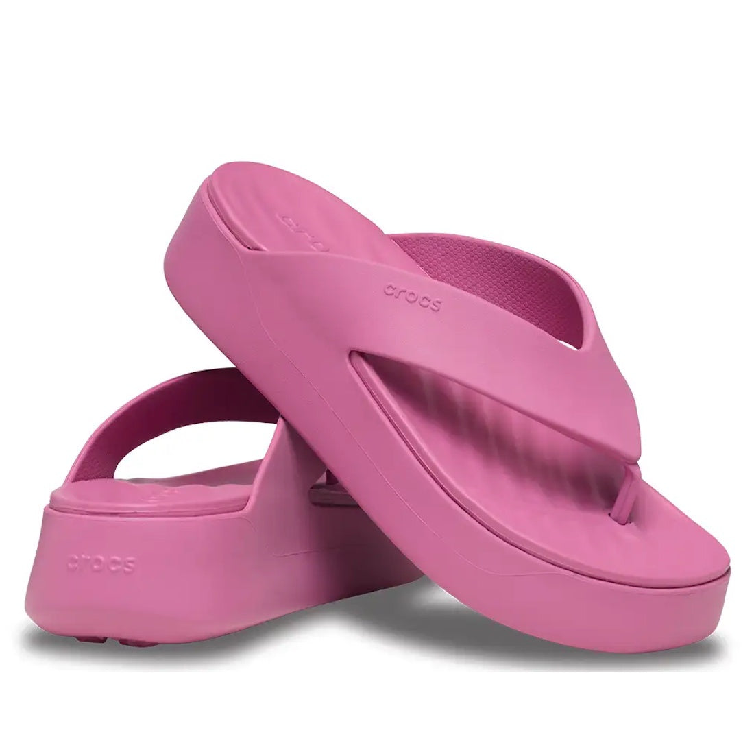 A pair of Crocs - Womens Getaway PLATFORM Flip Sandal Quiet Rose Pink from the Getaway Collection, featuring one sandal standing upright and the other on its side to display the thick platform sole with Free Feel Technology and textured straps that highli