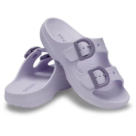 A pair of Crocs Womens Saturday Enamel Buckle Purple Halo Sandal Slides, featuring two adjustable straps with enamel buckles, are shown with one sandal resting on its side behind the other against a white background—delivering signature Crocs Comfort in e