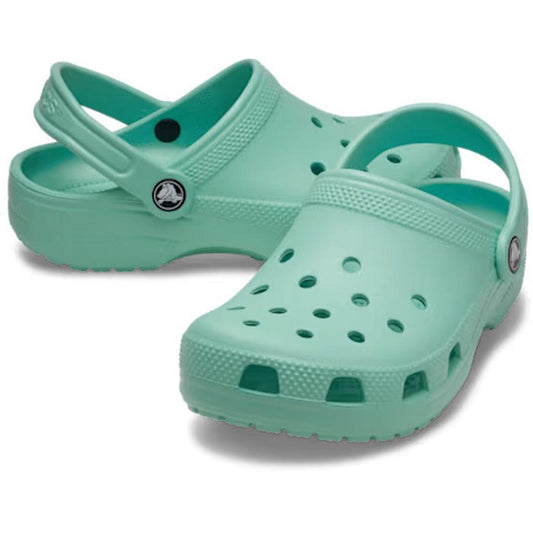 A pair of Crocs Kids - Classic Clog Retro junior youths clogs in green, featuring heel straps and ventilation holes, displayed on a white background.