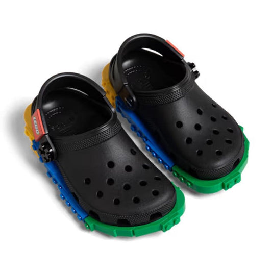 A pair of Crocs Kids’ LEGO® Creativity Clog Black Multi, featuring colorful LEGO-style bricks around the soles and straps, customizable with Jibbitz charms for a fun, personalized look.