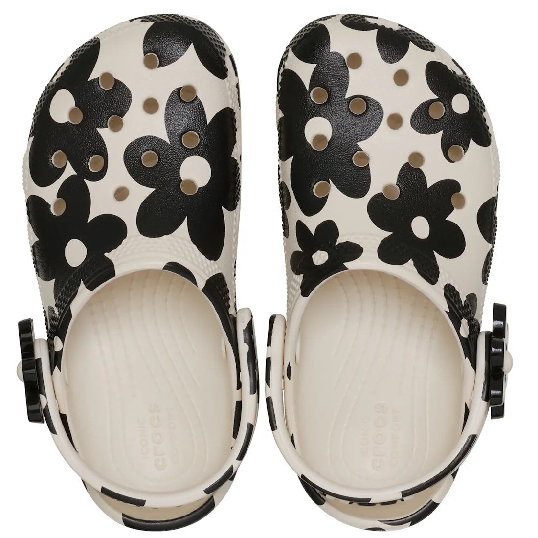 A pair of Crocs Kids Toddlers - Classic Clog K Pop Petals Off White Black sandals featuring cream-colored uppers with black flower print patterns and black heel straps, viewed from above and combining signature Crocs comfort with a stylish flair., 1984455