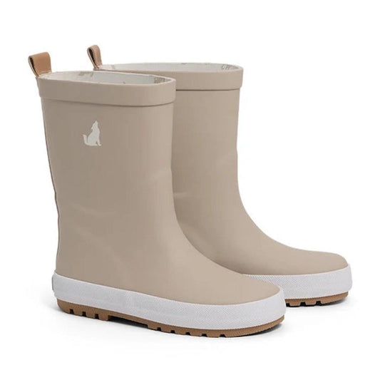 Pair of CryWolf Rain Boots Ash for children, taupe-colored and crafted from natural rubber, featuring white soles and a small dog silhouette logo on the side. The boots include tan pull tabs at the back for easy wear.