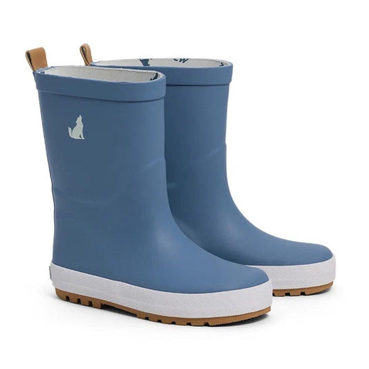 A pair of CryWolf Rain Boots in Highland Blue, expertly crafted from natural rubber for children, featuring tan pull tabs, white outsoles with brown treads, and a small white wolf silhouette on the outer upper side of each boot—ideal for little ones looki