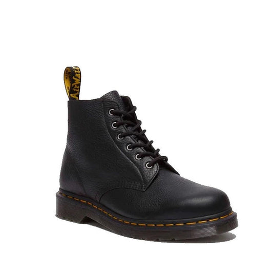 The Dr Martens 101 UB Black Ambassador 6 Eye Leather Boot features soft leather, yellow stitching on the sole, a thick tread, and a signature yellow pull tab at the back.