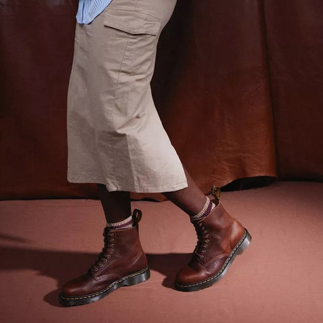 A model wearing a skirt, striped crew socks in beige and brown and Dr Martens Amabssador leather boots in cashew tan. In a walking stance showing the outer foot of the right foot & the inner of the left foot.,
190665662757,
190665662764,
190665662788,
190