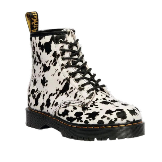 The Dr Martens 1460 Bex Dalmatian Hair On Leather Lace Up Boot features a bold black and white Dalmatian print, Goodyear welted black sole with yellow stitching, and a back pull tab accented with yellow text.