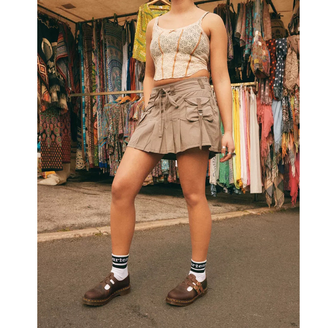 Person wearing a patterned top and beige skirt standing in front of a clothing store with racks of clothes wearing dr martens 8065 mary janes in crazy horse brown looking worn and antique., 190665588941, 190665588958, 190665588965, 190665588972, 131646546