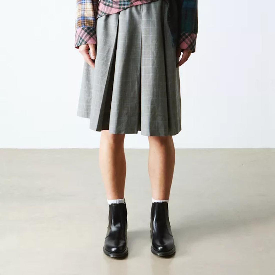 Person wearing a gray pleated skirt, standing front on with Dr Martens Black Flora Chelsea black boots with a finer sole and toe on a plain background.,
190665698183,
190665698190,
190665698206,
190665698220,
190665698237,
190665698244,, 190665698183, 190