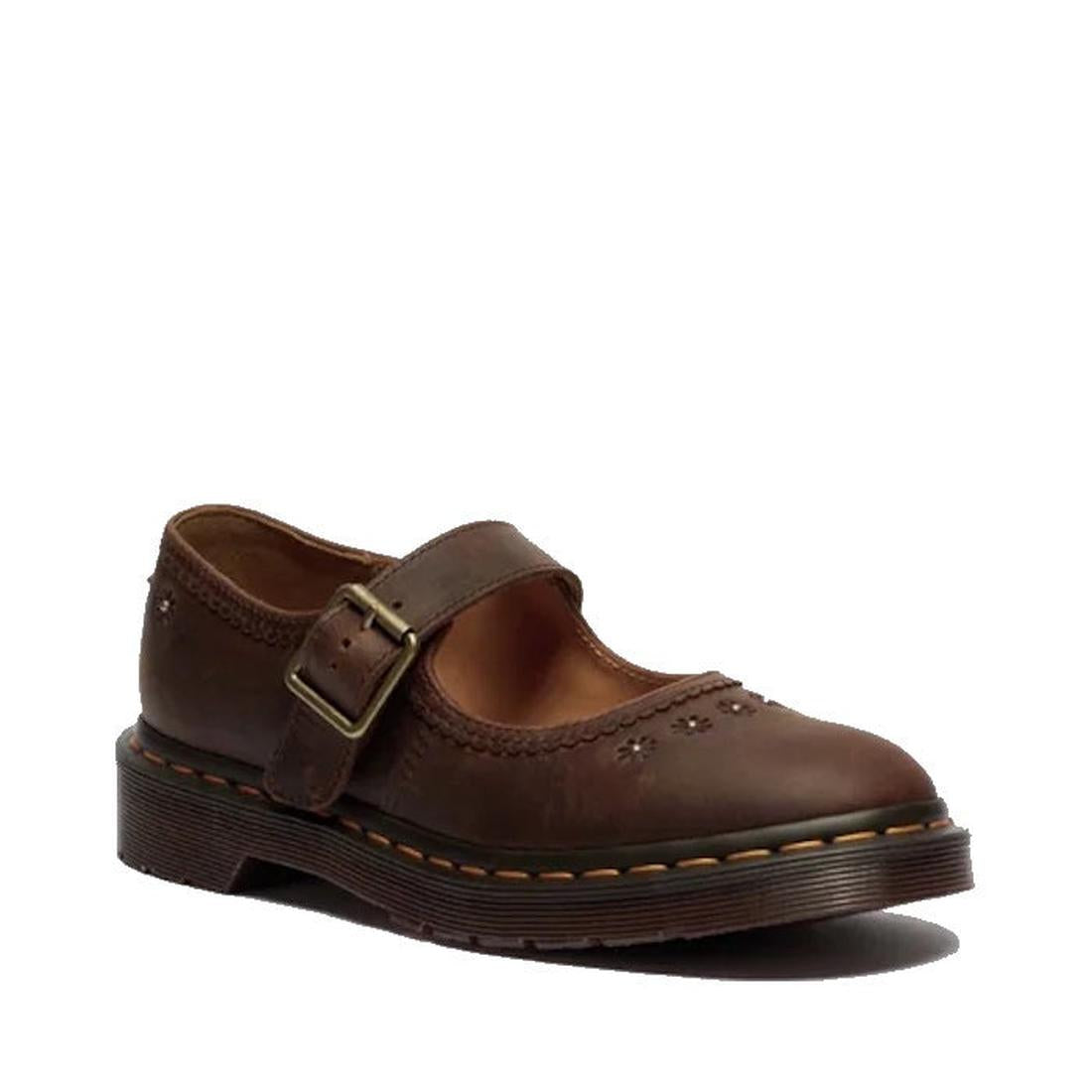 The Dr Martens Mary Jane Flower in Dark Brown Crazy Horse leather features a thick sole, decorative stitching, floral cutouts, and a brass buckle strap across the top.