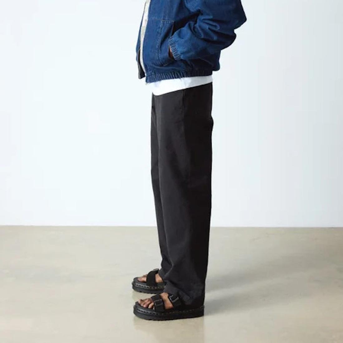 Indoors on a light floor, someone wears black pants, a blue jacket, and Dr Martens Myles Black E.H Long Napped Suede Sandals with distinctive thick Zebrilus soles; only the sandals and lower body are visible., 49269, 190665796711, 190665796728, 1906657967