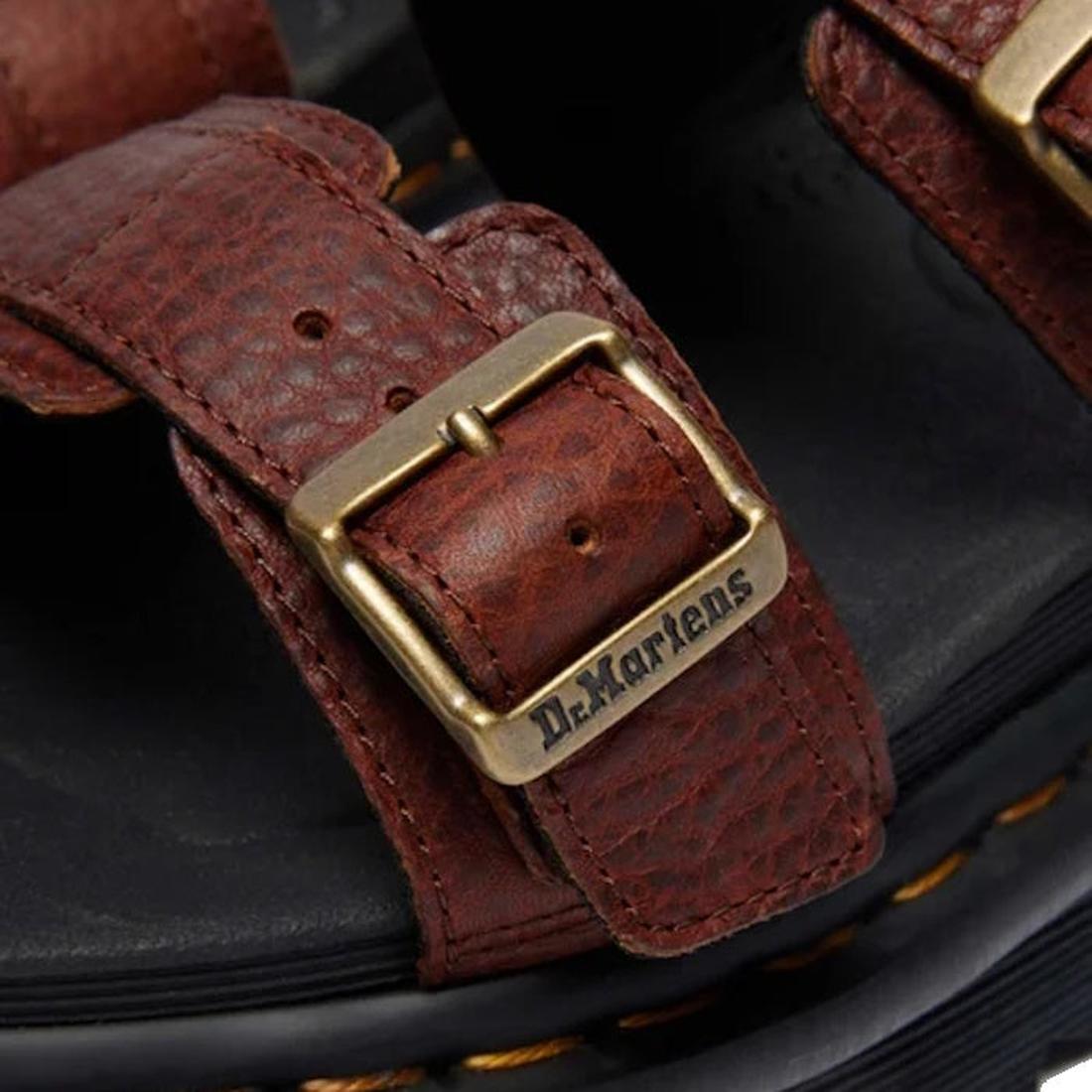 Close-up of the Dr. Martens Myles Cashew Ambassador Brown Leather Sandal strap with brass buckle engraved with Dr. Martens, highlighting texture, stitching, and the black EVA Zebrilus sole edged in yellow stitching., 49260, 190665772081, 190665772098, 190
