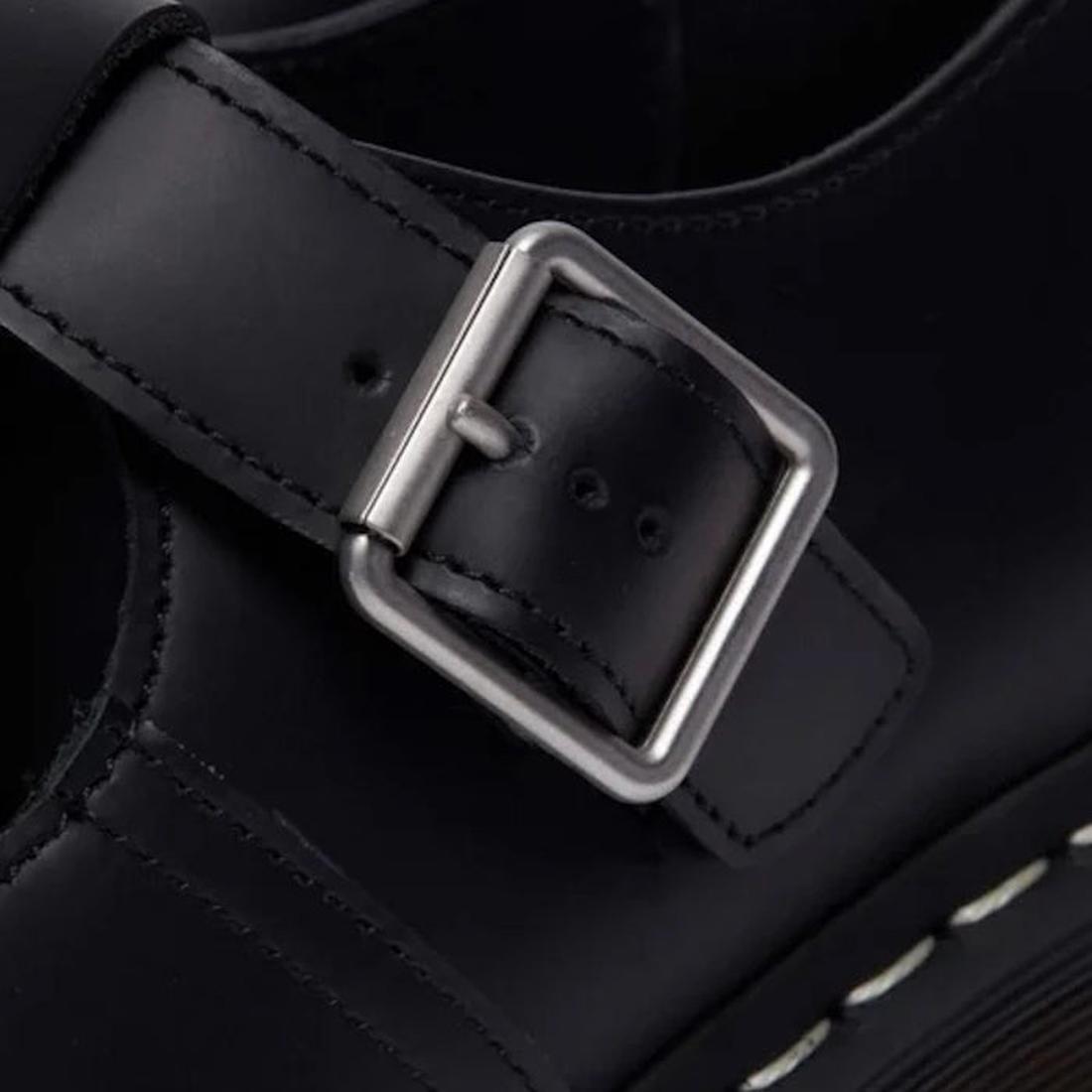 Close-up of a black leather DR Martens Polley T Bar with a silver buckle on a dark background.,
190665696905,
190665696912,
190665696936,, 45112, 45113, 190665696905, 190665696912, 190665696936, 45118, 45119