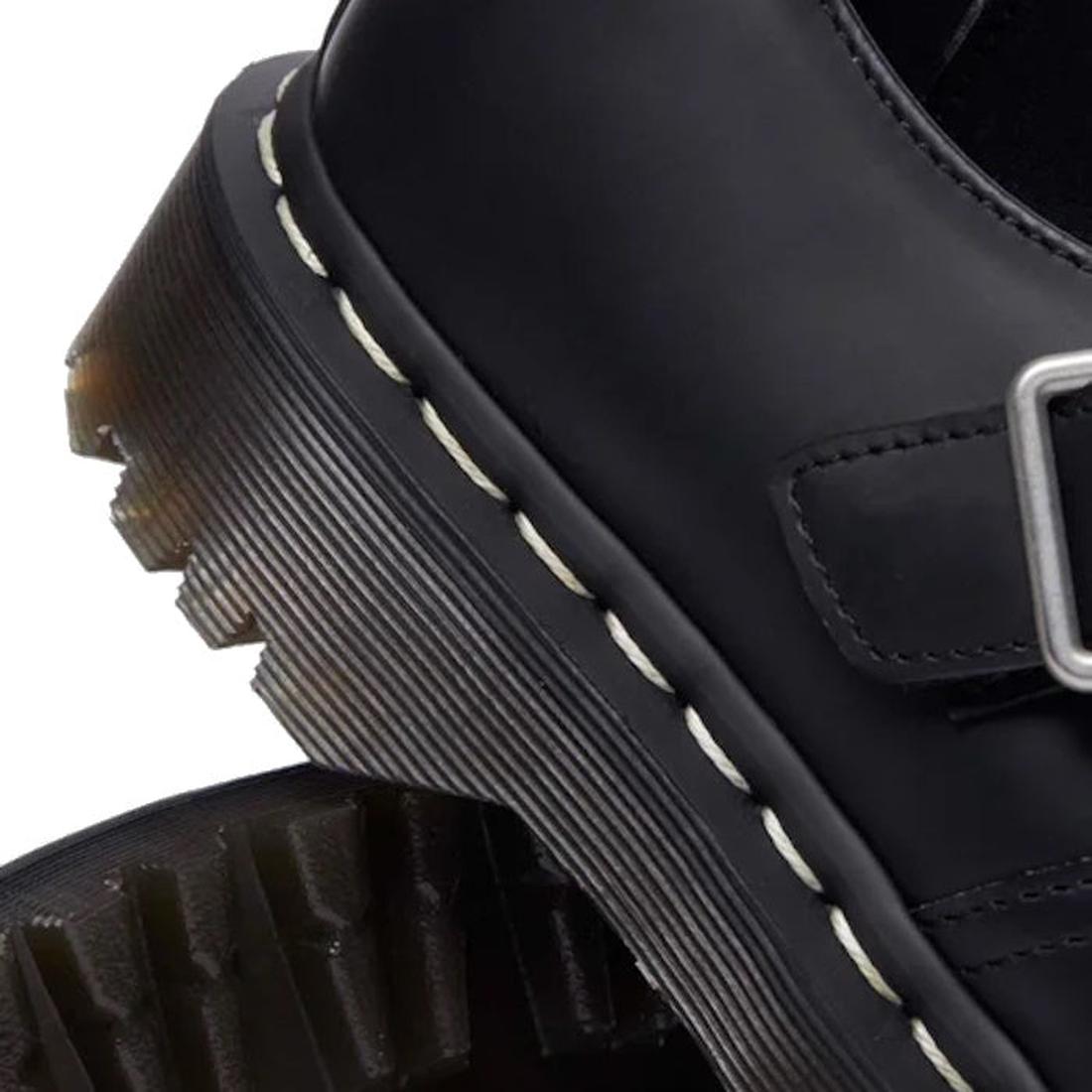 Close-up of a black leather Polley T Bar Dr Martens  shoe heel with a buckle and white stitching on a white background.,
190665696905,
190665696912,
190665696936,, 45112, 45113, 190665696905, 190665696912, 190665696936, 45118, 45119
