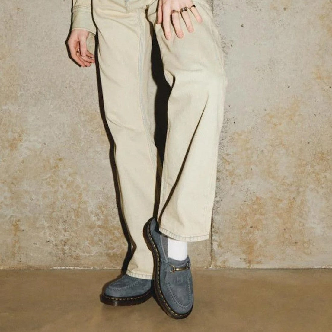 A cozy scene showing legs in beige pants and white socks, wearing Dr Martens Adrian Snaffle Loafer—blue nubuck with sturdy sole.  ksnz, 190665630039, 190665629958, 190665629965, 190665629972, 190665629996, 190665630008, 190665630015