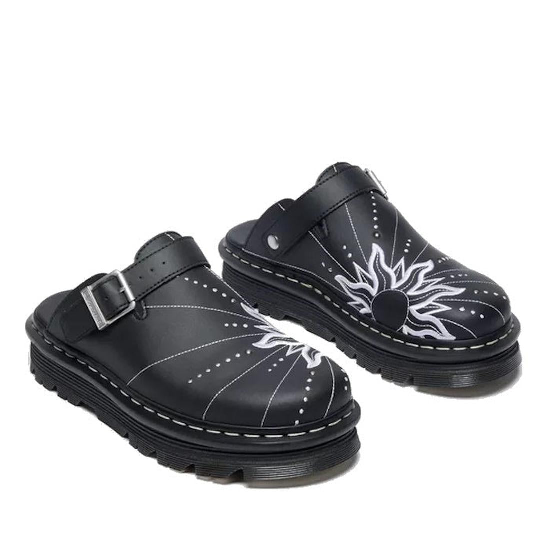 The Dr Martens Zebzag Mule Solar Flare Genix Nappa Black features black slip-on clogs with thick ergonomic soles, white stitching, buckle straps, and bold white sunburst celestial embroidery on each top., 190665758818, 190665758825, 190665758832, 19066575