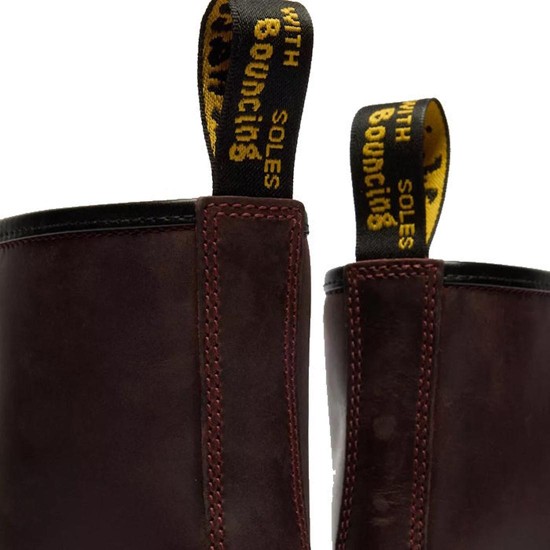 Close-up of two Dr Martens 1460 Cherry Red Crazy Horse Waxy Leather 8 Eye Boots with yellow and black pull tabs reading WITH BOUNCING SOLES in uppercase., 190665786835, 190665786842, 190665786859, 190665786873, 190665786880, 190665786897, 190665786910, 50
