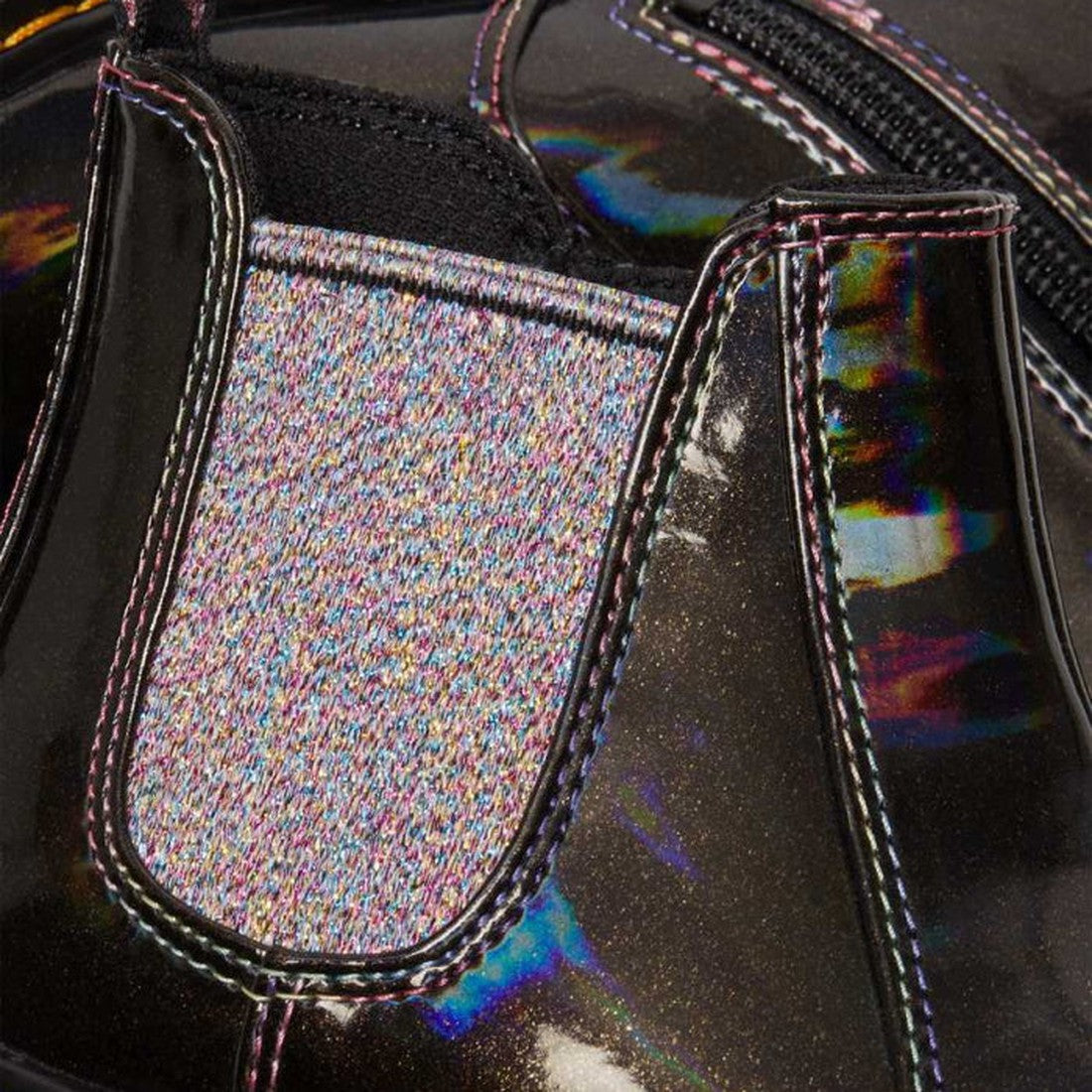 Close-up of the Dr Martens Kids Juniors 2976 J Chelsea Boot in Black Lightshow Sparkle Rays, featuring a shiny black finish, iridescent reflections, glittery multicolored elastic side panel, visible stitching, and zipper detail., 190665495171, 19066549519