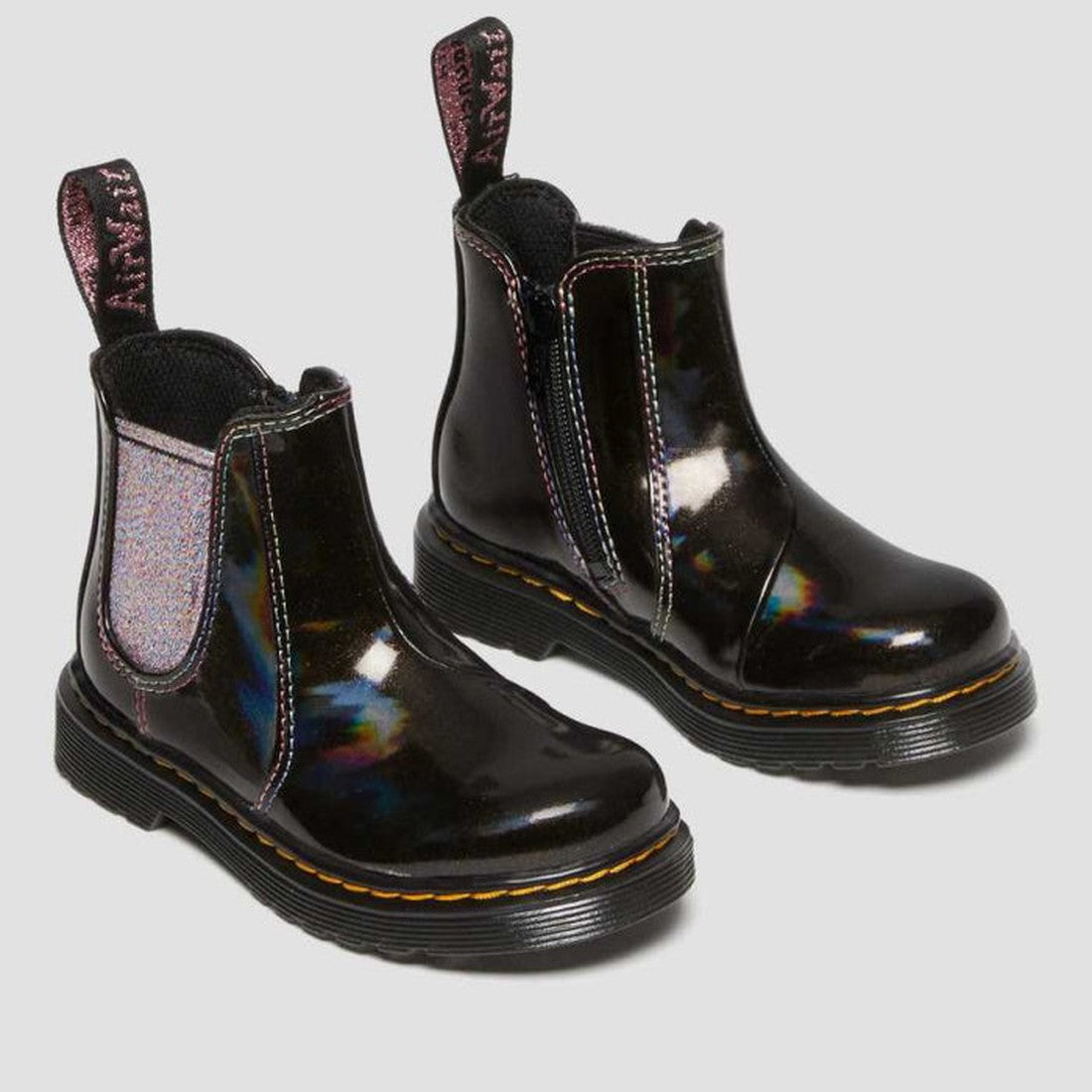 The Dr Martens Kids Toddlers 2976 T Chelsea Boot Black Lightshow Sparkle Rays (UK8) features shiny black uppers, iridescent side panels, yellow stitching, and pull tabs, displayed on a light gray background., 190665494914, 190665494921