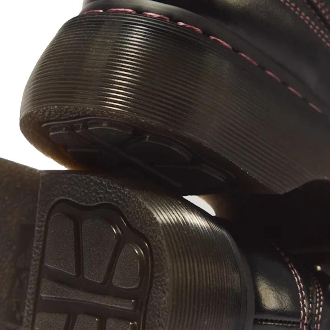 Close-up of the Goodyear welted soles and grooved rubber heels of two black Dr Martens Buzz 5i Hearts & Stars Milled Gloss Leather Shoes with pink stitching., 54732, 190665823745, 190665823752, 190665823776, 54736, 54737