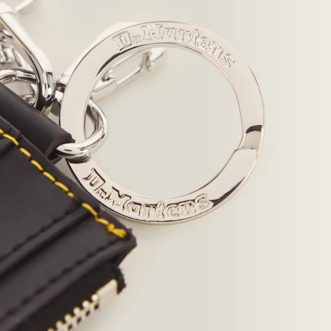 A close-up of the Dr Martens Cardholder Keyring Black Kiev Leather Bag Charm, featuring yellow stitching, a silver engraved keyring, and a detachable wrist strap., 190665739787