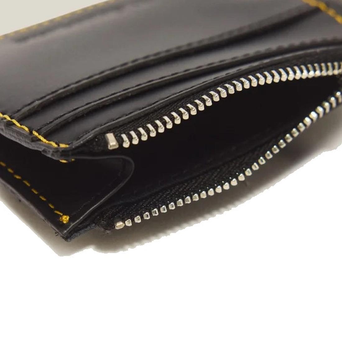 A close-up of the Dr Martens Cardholder Keyring Black Kiev Leather Bag Charm highlights its smooth black leather construction with yellow stitching, partially unzipped to reveal the zipper teeth and inner compartments. This sleek accessory includes a prac