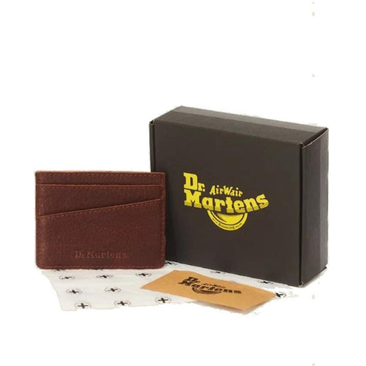 The Dr. Martens Cardholder II Cashew Ambassador Leather Wallet is shown in brown, positioned beside a black Dr. Martens box, a branded card, and logo-printed tissue paper.