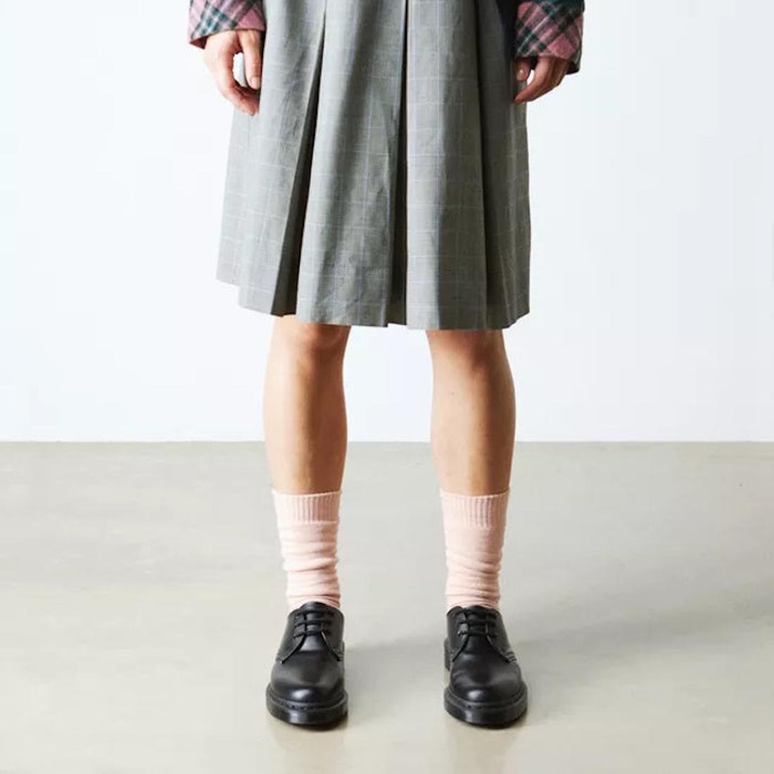 A lower body in a grey skirt shows black lace-up shoes with sturdy soles, paired with Dr Martens Socks Double Doc Sock Powder Pink Unisex.  ksnz, 190665728293, 190665728286