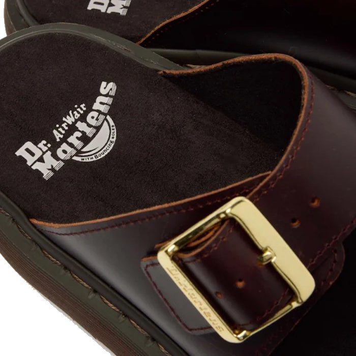 Close-up of the Dr Martens Josef Charro Atlas Slide Sandal Leather in dark brown, showcasing a gold buckle and a visible white logo on the black cushioned insole.