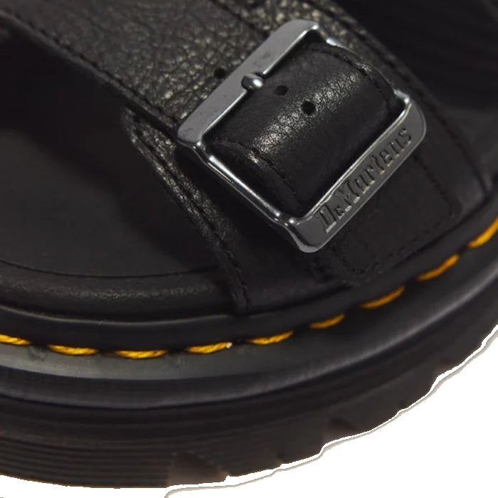 Close-up of a Dr Martens Zebzag Black Pisa Leather 3 Strap Sandal strap secured by a metal buckle, featuring yellow contrast stitching along the air-cushioned sole.
