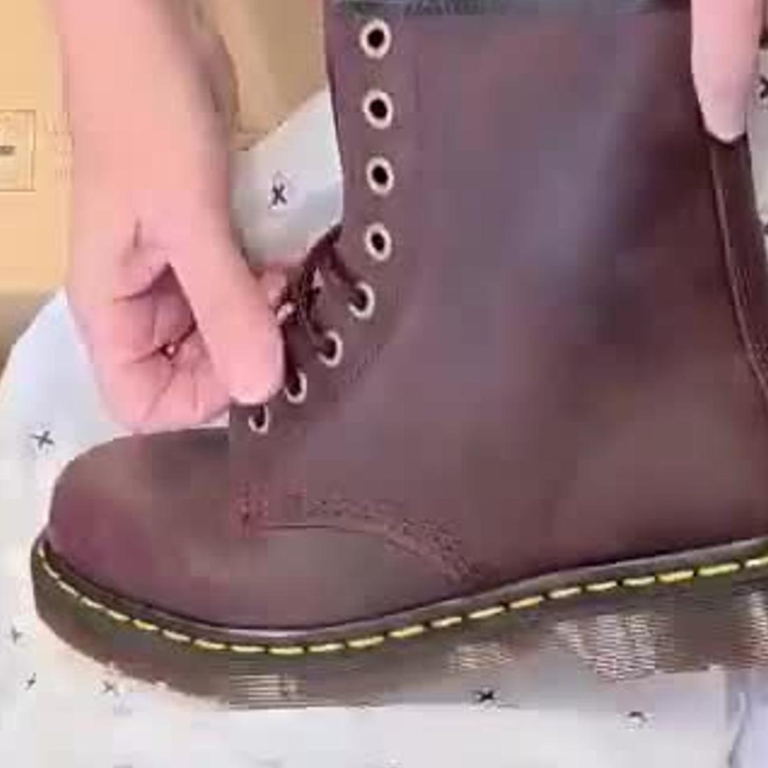 A person is lacing up a Dr Martens 1460 Cherry Red Crazy Horse Waxy Leather 8-eye Boot with yellow stitching on the Goodyear Welted sole, resting on white tissue paper with small black stars., 190665786835, 190665786842, 190665786859, 190665786873, 190665