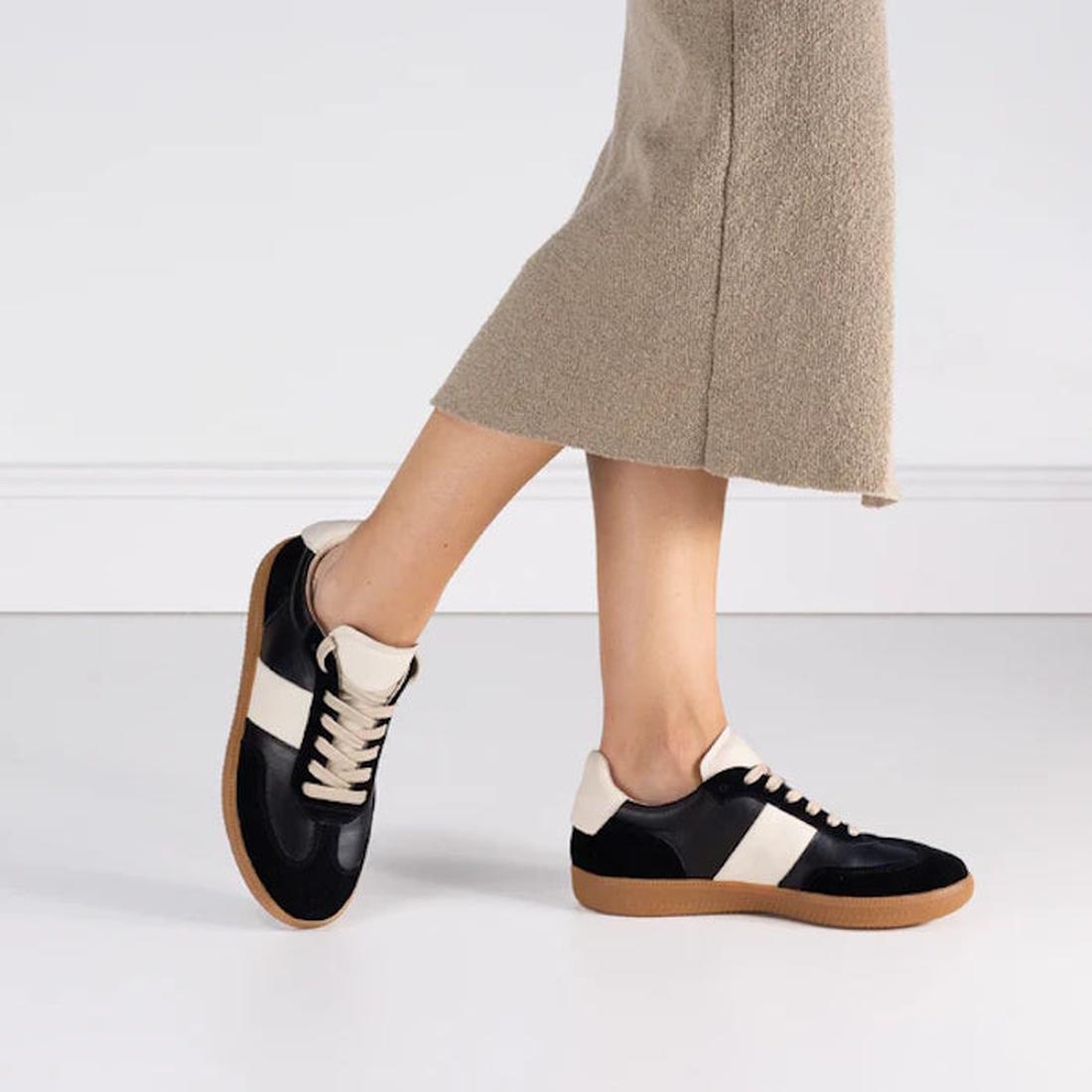 A person wearing a beige skirt and EOS Antigo Black Leather Lace Up Trainers stands against a plain white background., 51636, 9321191255088, 9321191255095, 9321191255101, 9321191255118, 9321191255125, 51642