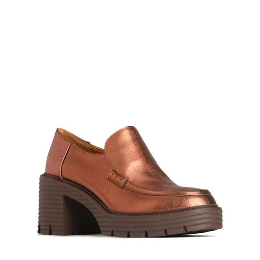 The EOS Malia Rusty Metallic Heeled Leather Shoe is a copper-toned loafer with a chunky block heel, square toe, and thick ridged dark brown sole, crafted from cashmere leather and shown on a plain white background.