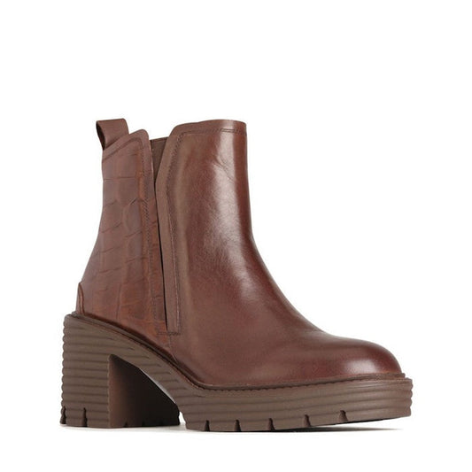 The EOS Malina Chestnut Heeled Leather Boot is a brown leather ankle boot with a chunky ridged block heel, platform sole, elastic side panels, back pull tab, and textured detailing on the heel.