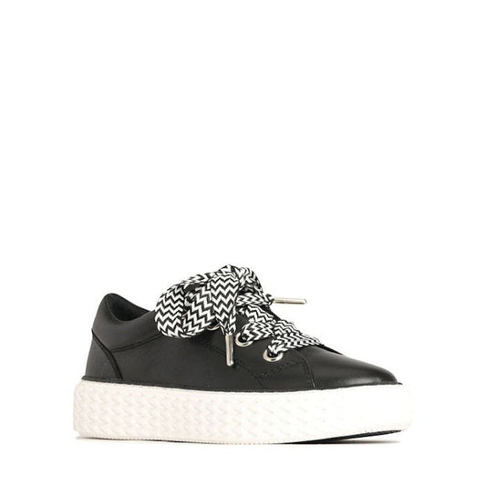 The EOS Trinsic Black Leather Lace Up Trainer features a thick white sole, oversized black and white zigzag laces, and a chevron-patterned outsole, shown on a plain white background.