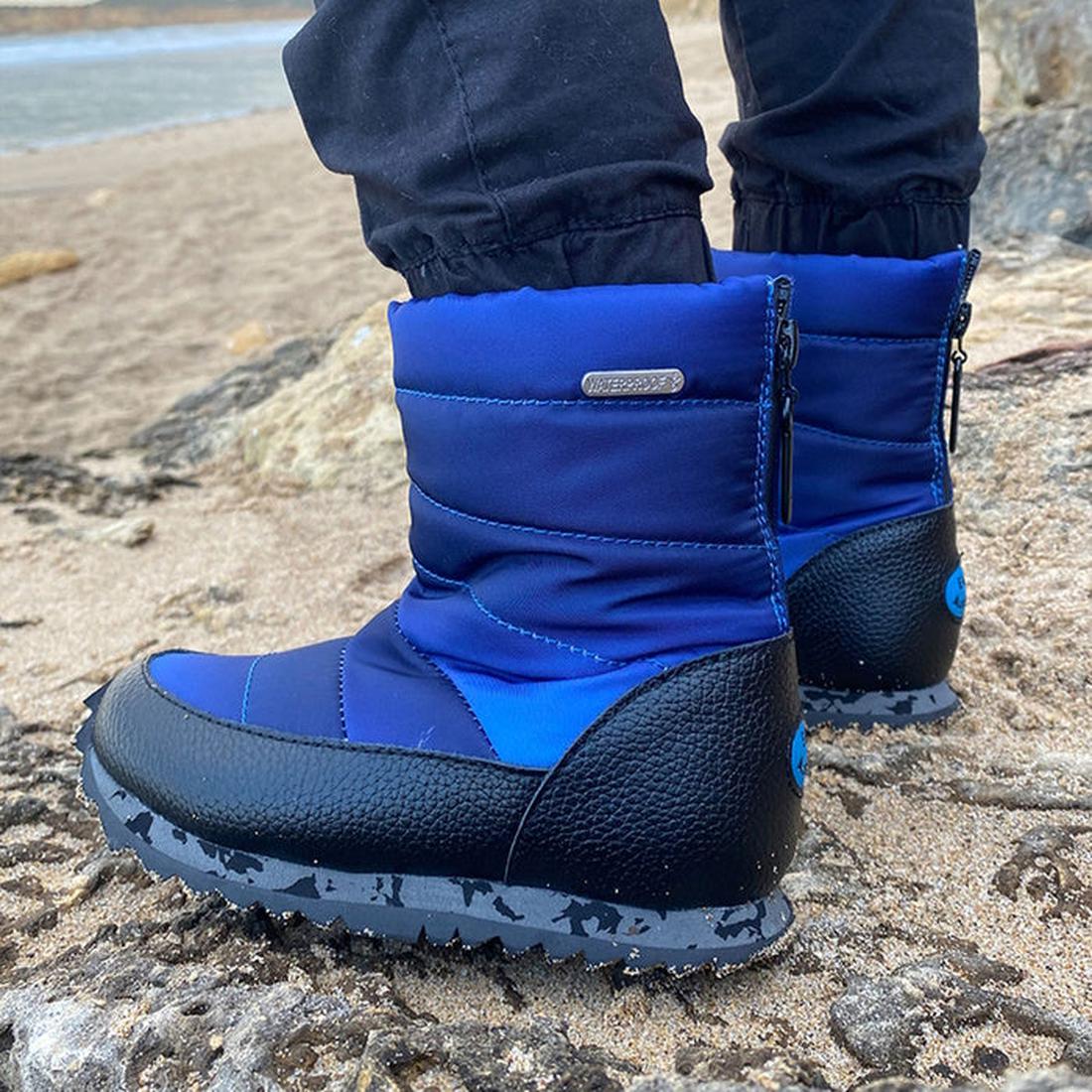 A child in EMU NZ Kids Tarlo Midnight Boot steps by the water—navy waterproof boots with sturdy soles, brand label, and snug wool lining.  ksnz