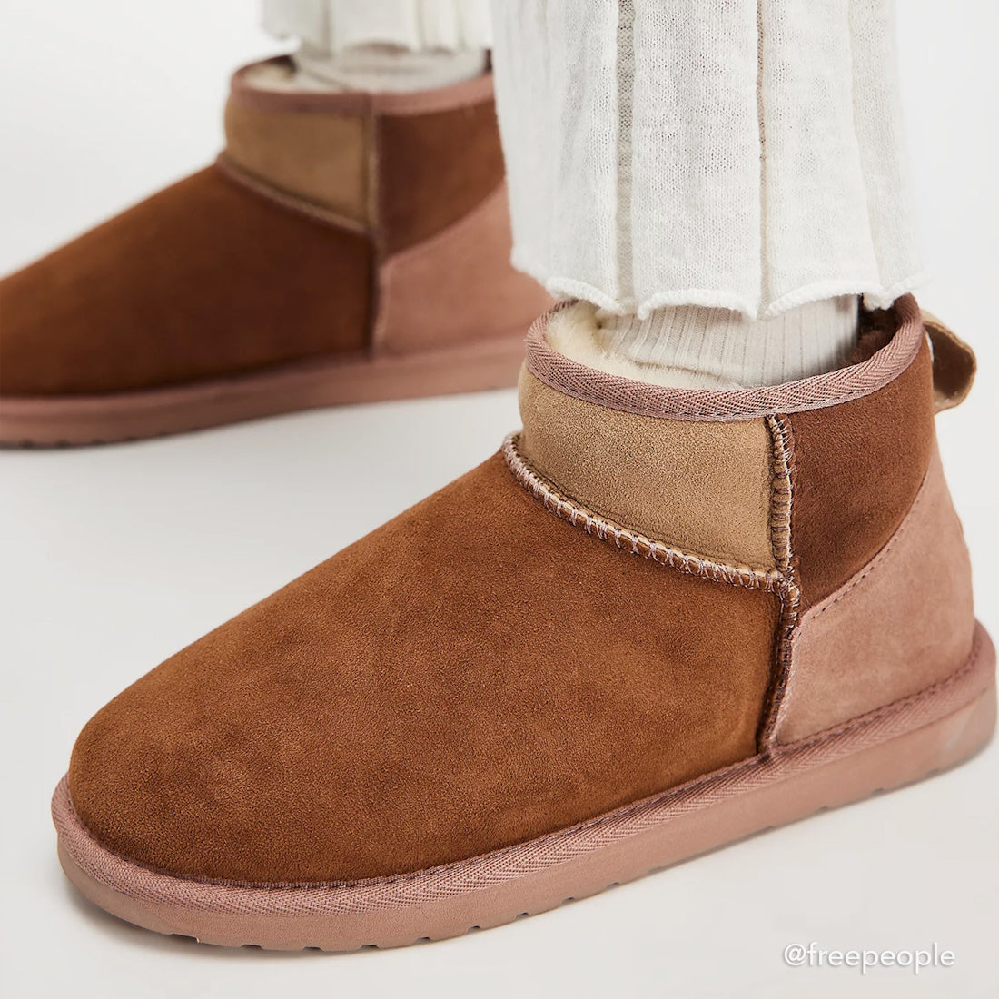 Close-up of a person wearing EMU Stinger Micro Patchwork Sheepskin Chestnut Wool Boots with white socks and light-colored pants. The chestnut boots feature soft sheepskin, water resistance, and a lighter brown panel at the back., 50669, 9330071977309, 933