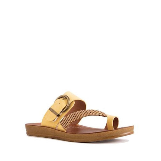 The Los Cabos Bria Sunset Light Flexible Sandal Jandal is a yellow women’s thong sandal with a flat brown sole, large buckle, and stylish straps across the top and toe, shown on a white background.