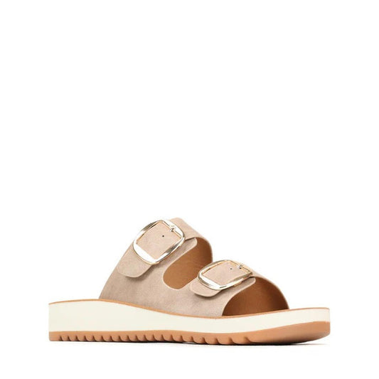 The Los Cabos Naara Taupe Adjustable Womens Summer Slide Sandal features two wide taupe vegan leather straps with large gold buckles, subtle arch support, a white elevated sole, and tan tread. Shown on a plain white background.