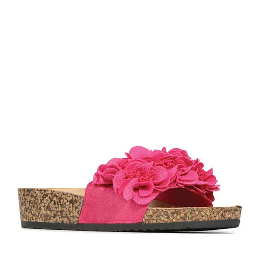 A side view of the Los Cabos Corsage Fuchsia Flower Women’s Slides in hot pink showcases a playful sandal featuring a cork sole and vibrant pink floral embellishments on the strap—perfect for adding a pop of color and feminine charm to your look.