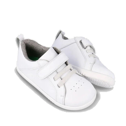 The Bobux Kids IWalk IW Pace Optical White Sneakers are unisex shoes with gray interiors, featuring a hook-and-loop strap, elastic laces, side view details, and durable rubber soles for comfort.