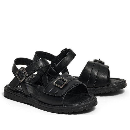 The Pretty Brave Phoebe Girls Black Leather School Sandal features black leather, crisscross straps, open toes, ankle straps, and adjustable metal buckles, shown against a white background.