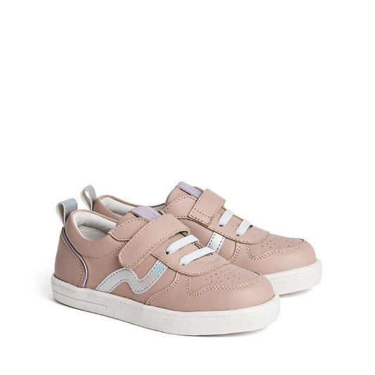 The Pretty Brave XO Trainer Blush features blush pink kids' sneakers with white soles, silver accents, two velcro straps, and elastic laces. The pair is displayed side by side on a plain white background.