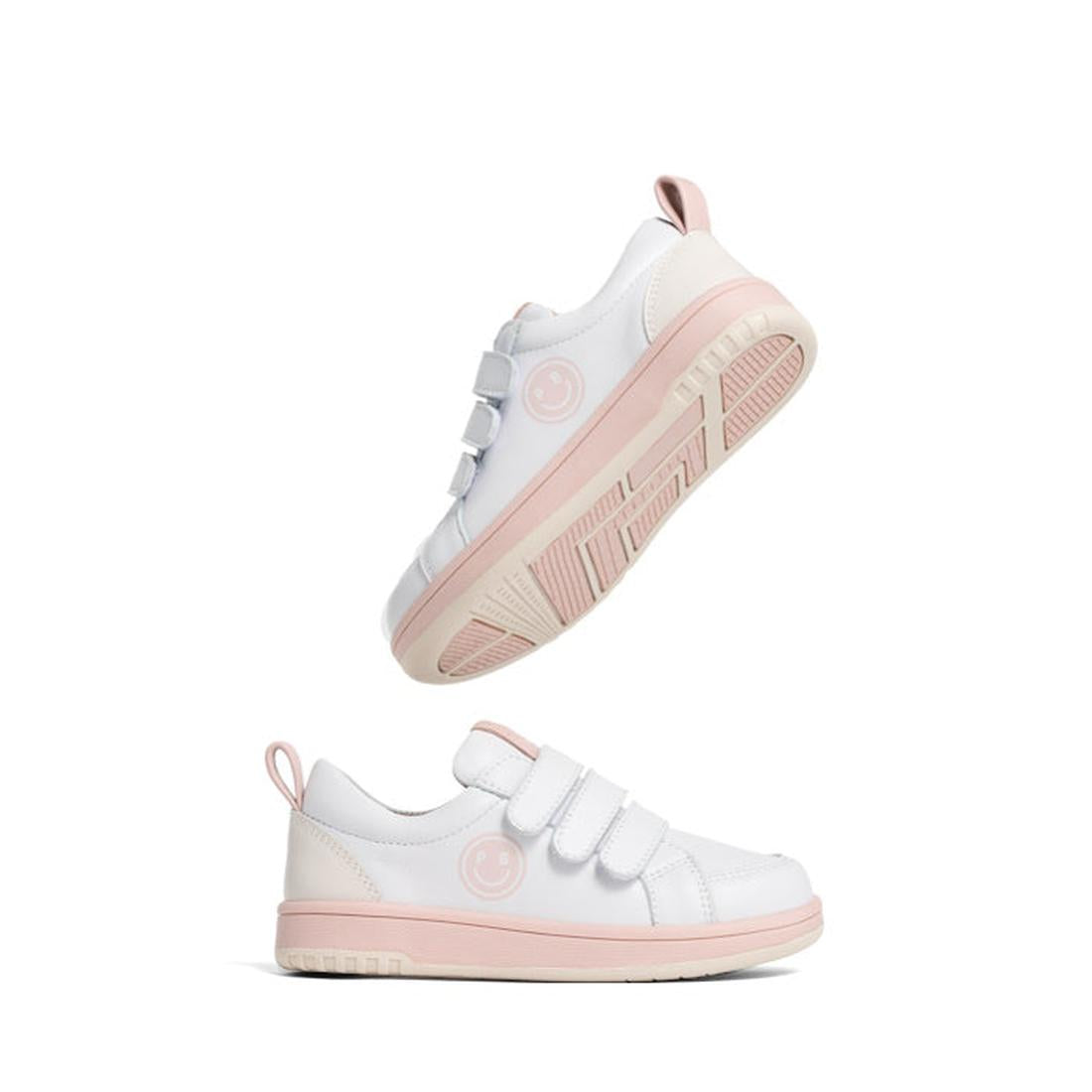 The Pretty Brave Happy Trainer White/Blush Sneaker features white leather, light pink accents, triple Velcro straps, and a smiling face logo. One shoe stands upright; the other is shown from a tilted, bottom-up angle., 40192, 9420075335905, 9420075335899,
