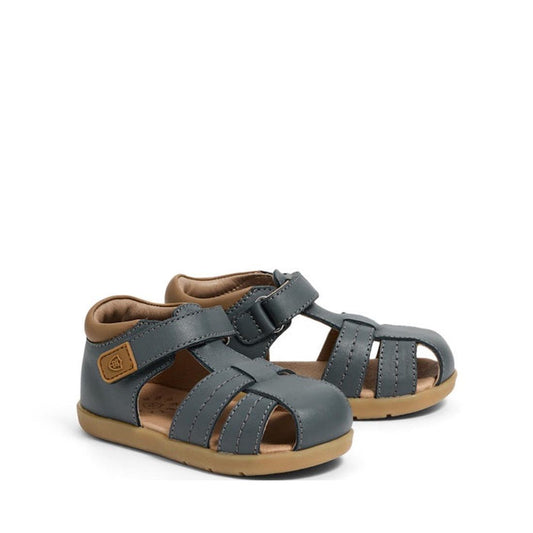 The Pretty Brave 1st Walker Theo Indigo Leather Closed Toe Sandal is a podiatrist-approved summer sandal in blue leather with tan soles, multiple straps, a supportive closed toe, and an ankle velcro fastening.